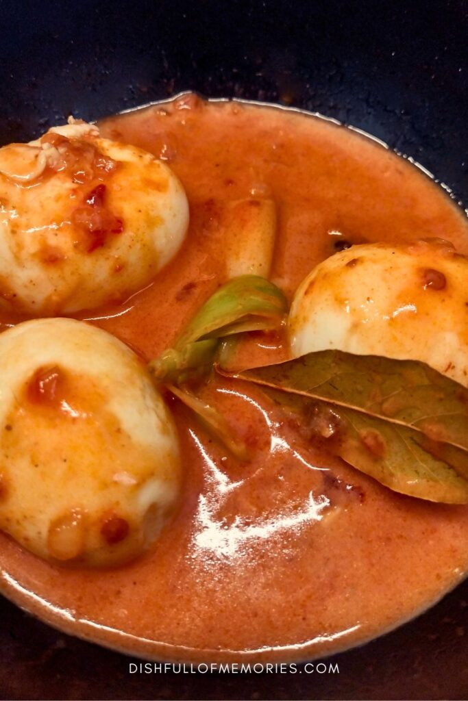 Pan with boiled eggs simmering in chili sauce with bay leaves.