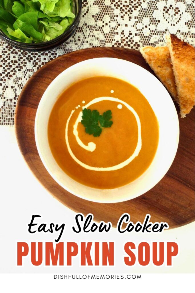 Bowl of homemade soup with cream, salad and toast on the side. Text on image: Easy slow cooker pumpkin soup. Dish full of memories dot com.
