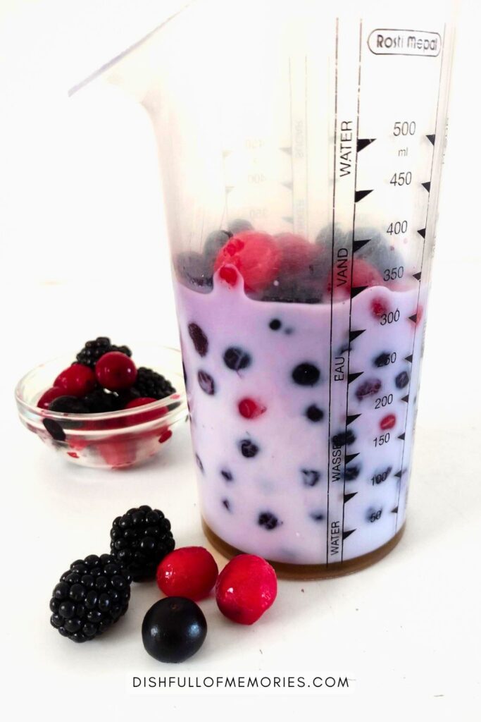 Berries and milk in mixing jar ready to blend into a smoothie.