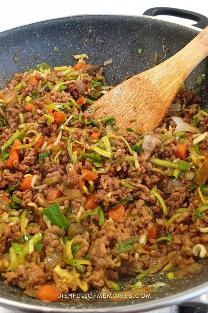 Meat and vegetable pastry filling being prepared in large pan.
