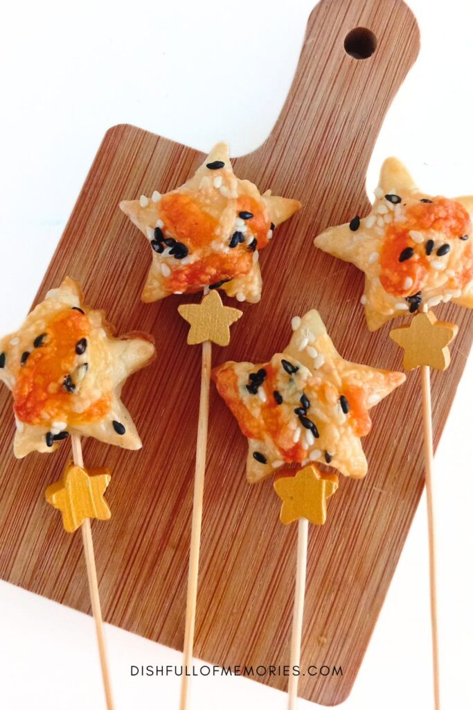 Puff pastry cheese star appetizers on stick on wooden serving board.